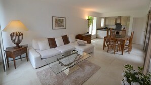 Ein modernes Wohnzimmer mit einem weißen Sofa, einem Glastisch und einem Essbereich mit Holzsesseln und einem Tisch.