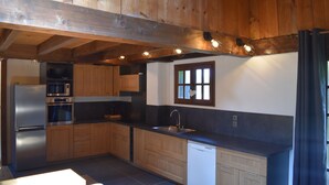A modern kitchen with wooden cabinets, stainless steel appliances, and a black countertop. - Chalet with 4 bedrooms - 8 people - (Ideal Family, Group of friends) (Les Contamines-Montjoie)