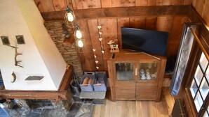 A cozy room with a stone fireplace, wooden cabinets, a television, and a stone wall. - Chalet with 4 bedrooms - 8 people - (Ideal Family, Group of friends) (Les Contamines-Montjoie)