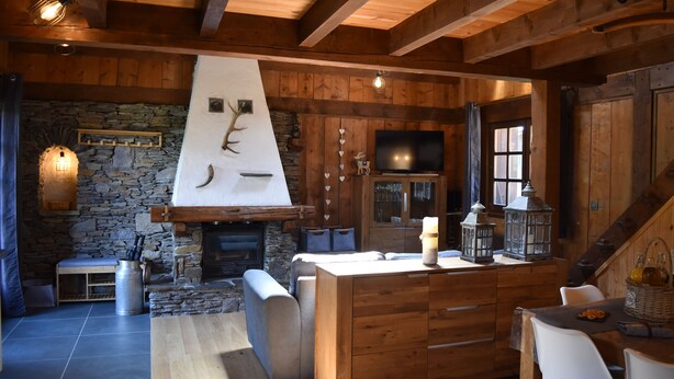 A rustic cabin interior with a stone fireplace, wooden beams, a stone wall, a television, and a dining area. - Chalet with 4 bedrooms - 8 people - (Ideal Family, Group of friends) (Les Contamines-Montjoie)