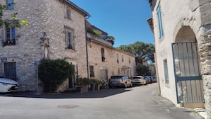 A narrow street lined with stone buildings, parked cars, and a clear blue sky. - STUDIO 15 min from Pont du Gard and Avignon—swimming and canoeing—1 hour from the sea and mountains (Rochefort-Du-Gard)
