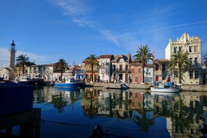 A waterfront with historic buildings, a lighthouse, and boats docked.