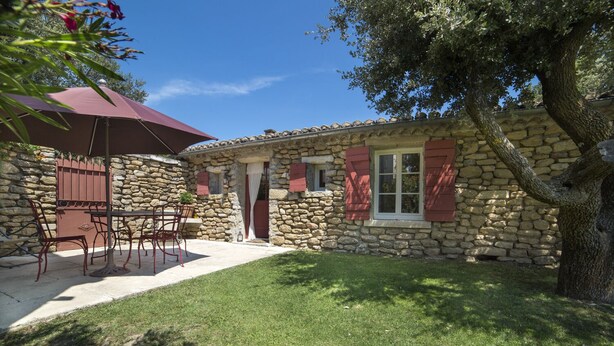 A stone house with a patio, a table with chairs, and a large umbrella. - LE PETIT MAS PROVENÇAL. POOL & AIR CONDITIONING VINEYARD VIEW (Grillon)