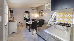 A compact kitchen with a dining area, a built-in oven, and a small refrigerator. - LE PETIT MAS PROVENÇAL. POOL & AIR CONDITIONING VINEYARD VIEW (Grillon)