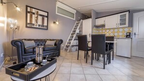 A compact living space with a sofa, dining table, chairs, and a kitchen area. - LE PETIT MAS PROVENÇAL. POOL & AIR CONDITIONING VINEYARD VIEW (Grillon)