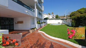 Un edificio moderno con piscina, césped cuidado y zona de patio.