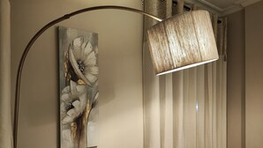 Una habitación con una lámpara moderna, un cuadro abstracto en la pared y un sofá estampado.