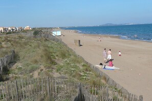 A beach with a wooden fence, a few people, and a small building in the background. - RARE-very nice house, portiragnes-plage .herault languedoc roussillon (Portiragnes)