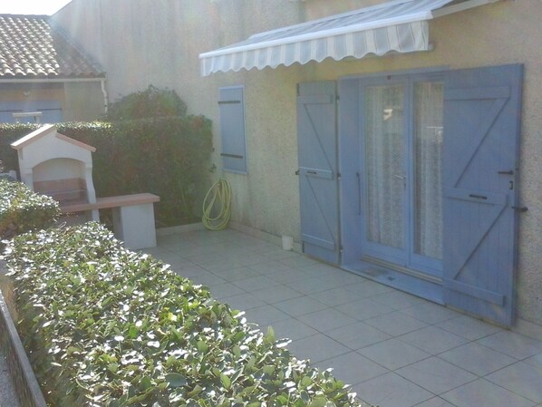 A patio area with a tiled floor, a small white structure, and a hedge. - RARE-very nice house, portiragnes-plage .herault languedoc roussillon (Portiragnes)