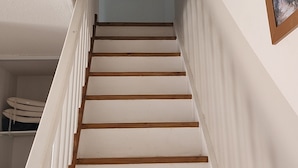 A staircase with white walls and wooden steps leading to a landing.