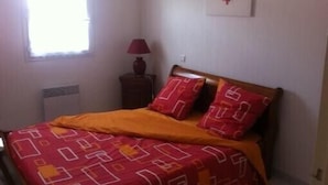 A bedroom with a bed, a window, a lamp, and a wall decoration.