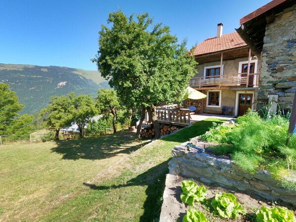 A stone house with a balcony, a wooden deck, and a view of mountains.
