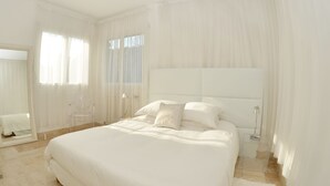 Ein geräumiges Schlafzimmer mit einem großen Bett, einem Nachttisch, einer Lampe und einem Sessel.