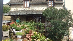 A stone house with a sloped roof and wooden windows. - Randonnée portes de l'Aubrac Vue sur Lac 4 pers 2 chambres 2wc Mandailles (Castelnau-De-Mandailles)