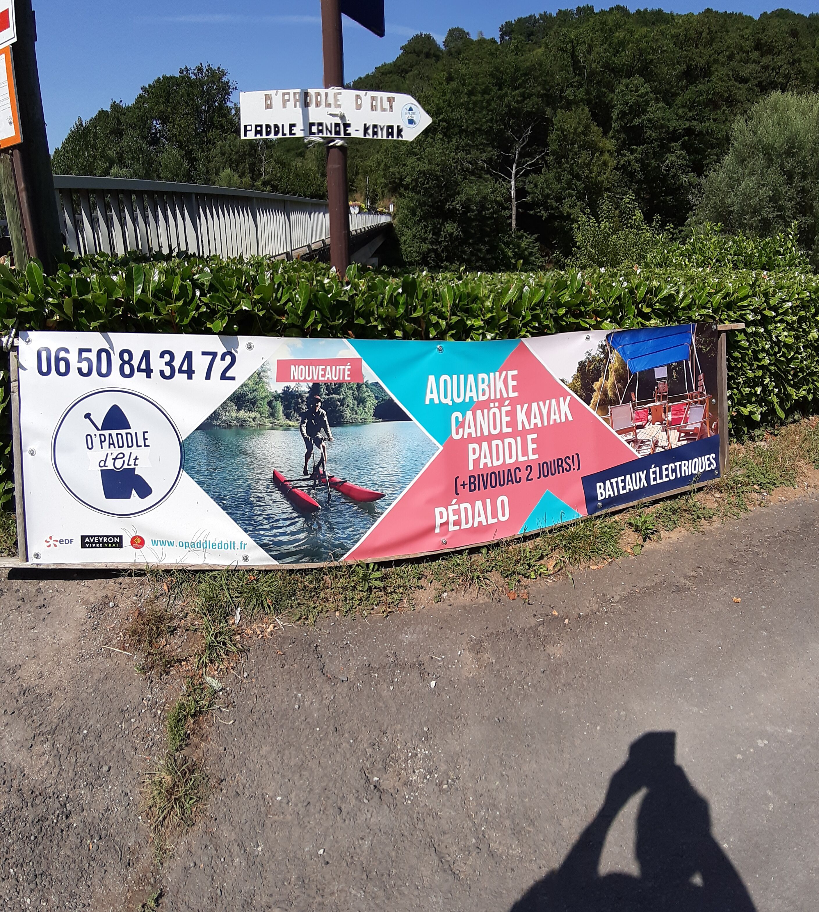 A signboard advertising paddle, canoe, and kayak rentals with contact information and a website URL.