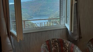 A room with a large window overlooking a hilly landscape. - Randonnée portes de l'Aubrac Vue sur Lac 4 pers 2 chambres 2wc Mandailles (Castelnau-De-Mandailles)