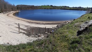 A large, calm lake surrounded by grassy areas and trees. - Randonnée portes de l'Aubrac Vue sur Lac 4 pers 2 chambres 2wc Mandailles (Castelnau-De-Mandailles)