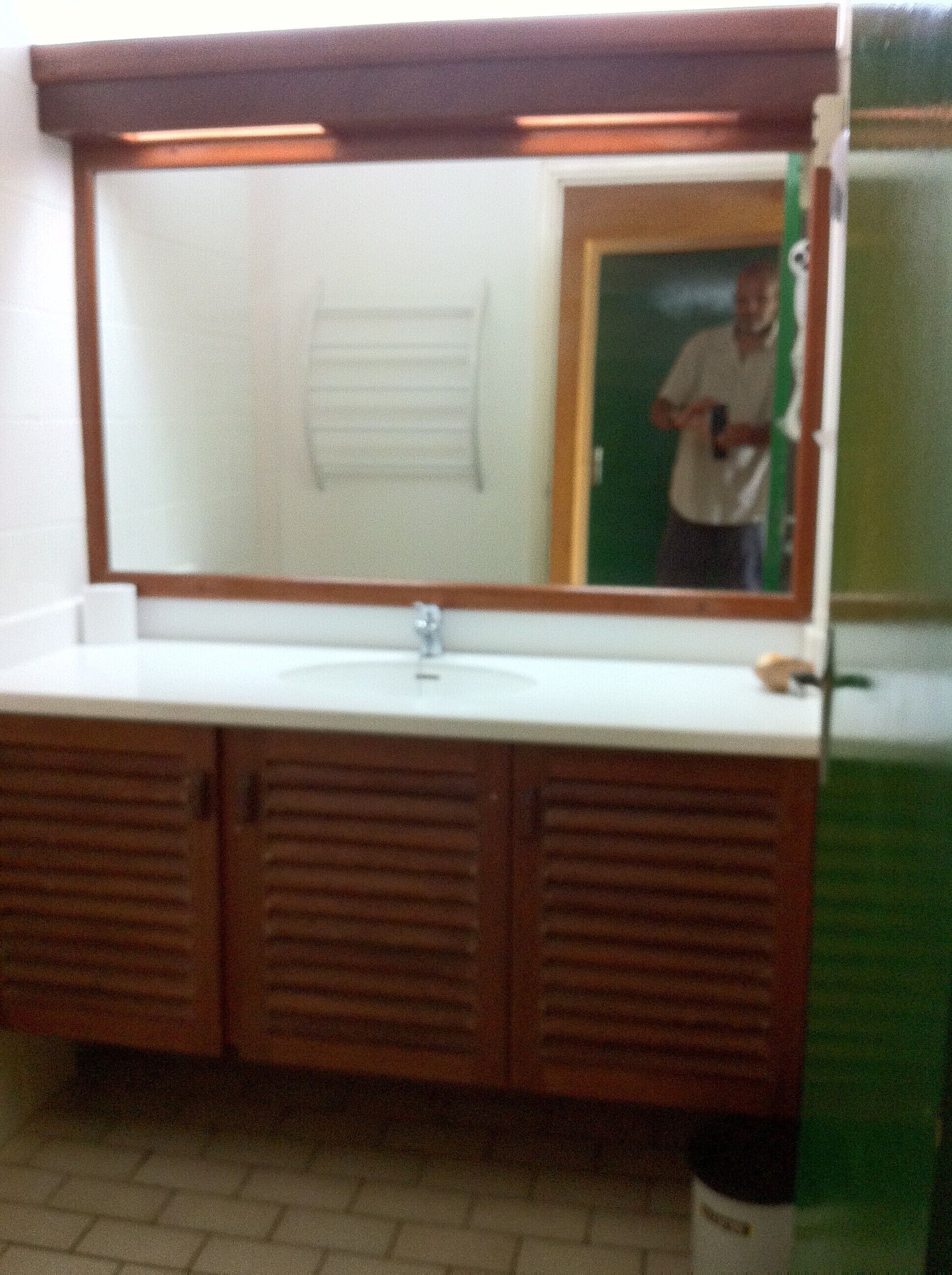 A bathroom with a large mirror, a sink, and wooden cabinets.