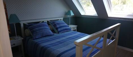 A bedroom with a bed, two nightstands, a lamp, and a window.