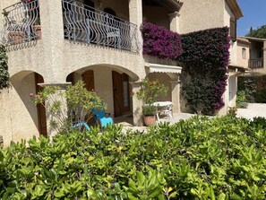 A building with a balcony, potted plants, and a small outdoor seating area. - Apartment in villa (Sainte-Maxime)
