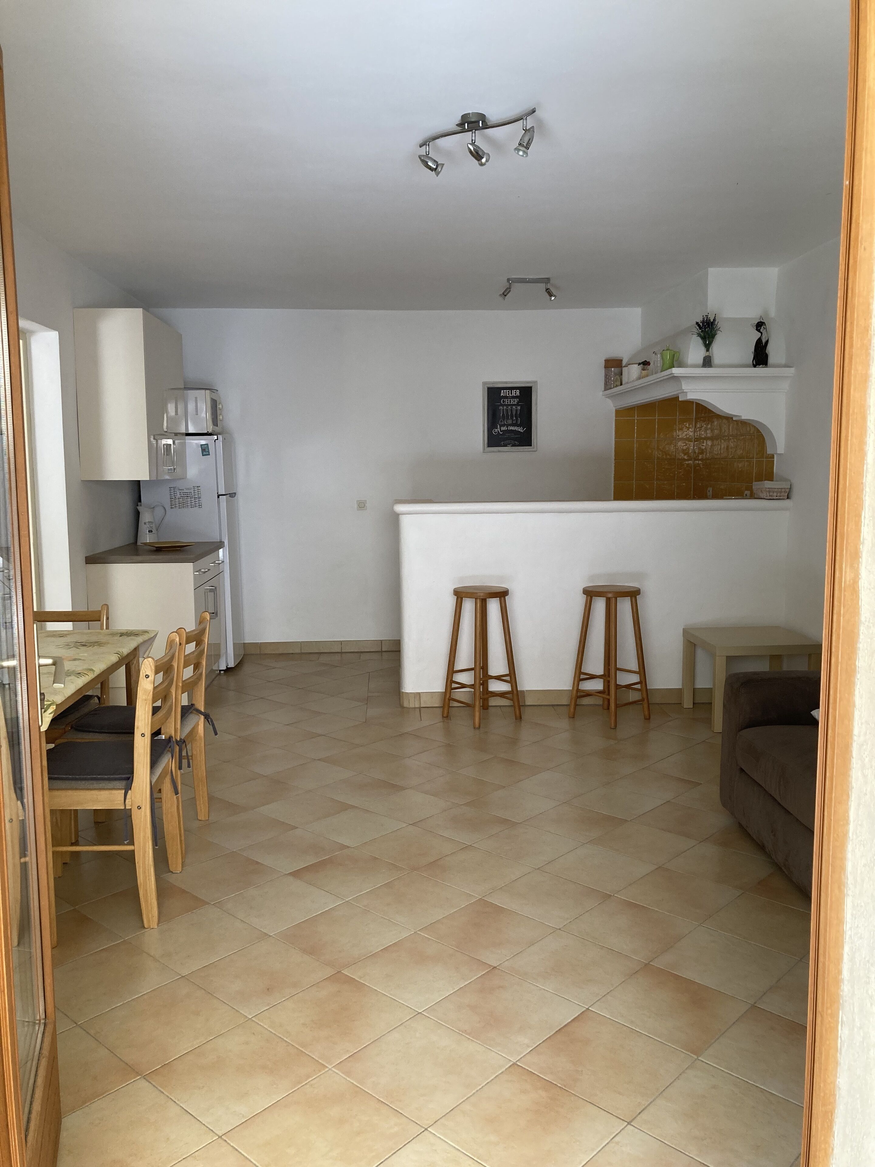 A compact kitchen with a dining area, a small bar, and a sofa.