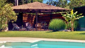 Une piscine avec des chaises longues et un espace de détente abrité.