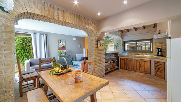 Une cuisine chaleureuse avec une table en bois, un panier de fruits et un îlot central.