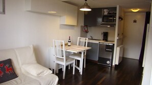 A compact living space with a dining area, kitchenette, and a sofa with a decorative pillow.