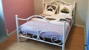 A bedroom with a white metal bed frame, a pink wall, and a wooden floor. - APARTMENT / VACATION RENTAL: 3 BEDROOMS, FOR 1 TO 6 PEOPLE (Vayrac)