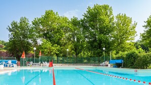 Piscina con corsie ben delimitate, circondata da una recinzione verde e alberi.