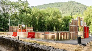 Un campo da basket con una recinzione di legno, un canestro e una panchina.