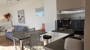 A modern kitchen with a dining area, a sofa, and a coffee machine. - Apartment facing the SEA and BEACH with view of POND and MOUNTAIN (Canet-En-Roussillon)