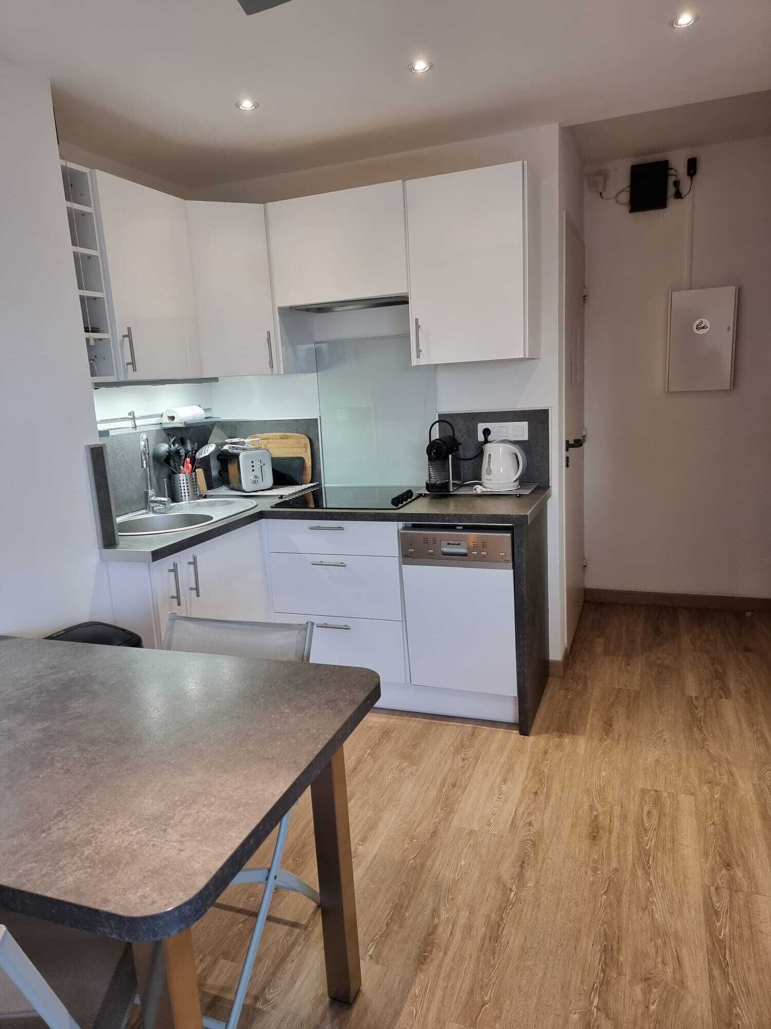 A compact kitchen with white cabinets, a sink, a coffee maker, and a toaster.