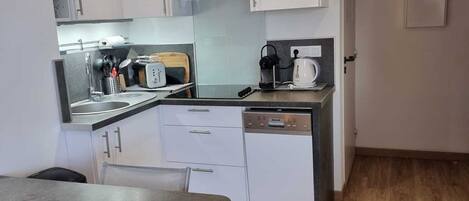 A compact kitchen with white cabinets, a sink, a coffee maker, and a toaster.
