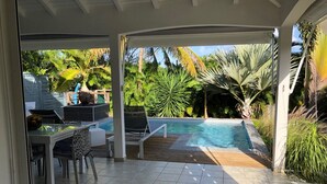 A covered outdoor area with a pool, lounge chairs, and a dining table. - Villa Majeya - Modern comfort, exotic setting near the beach                    (SAINT-FRANCOIS)