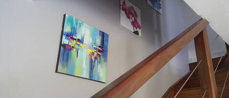 A staircase with wooden handrails and a white wall with three framed artworks.