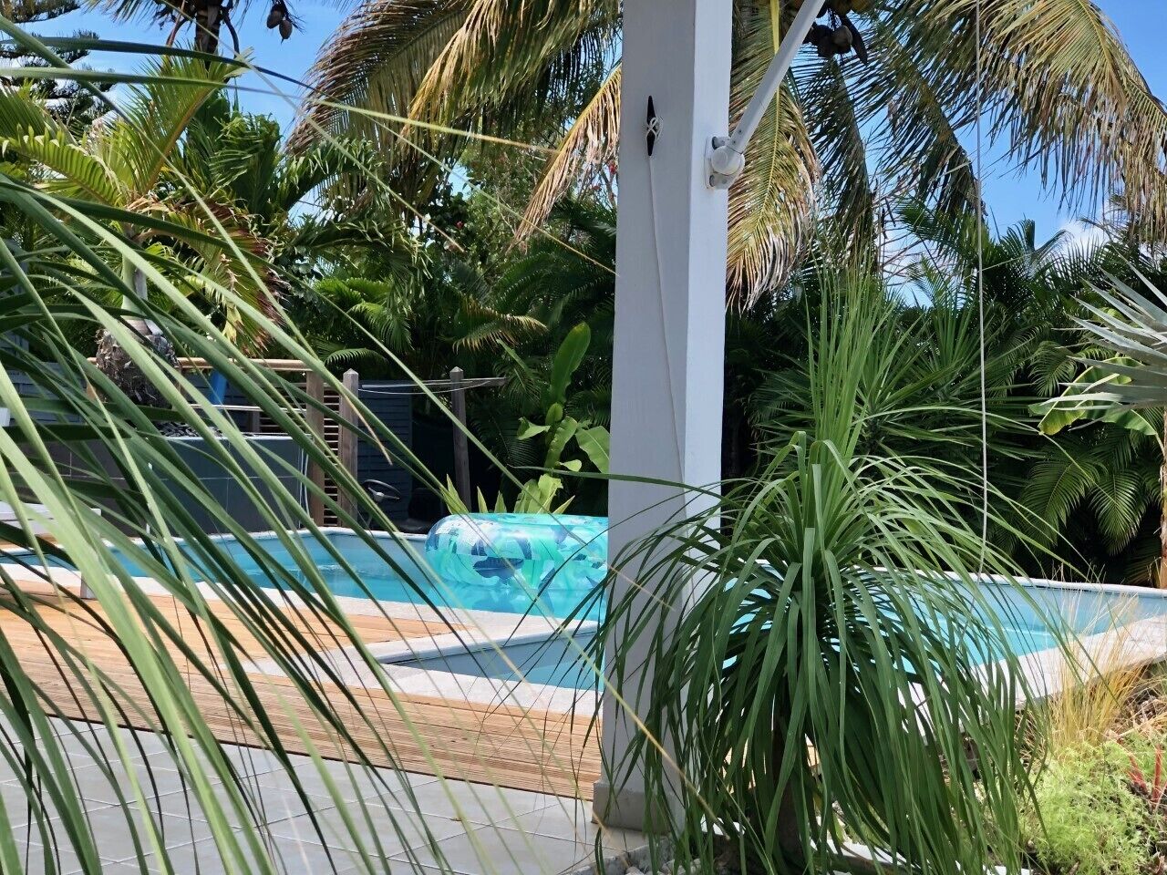 Una piscina rodeada de exuberante follaje y un pilar blanco.