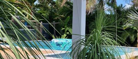 Una piscina rodeada de exuberante follaje y un pilar blanco.