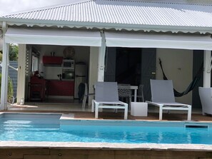 A pool area with white lounge chairs and a covered patio.