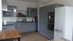 A modern kitchen with grey cabinets, a wooden table, and a refrigerator. - Breton family house with magnificent sea views (Carantec)