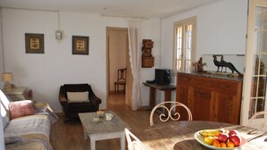 A cozy living room with a sofa, a small table with a bowl of fruit, and a wooden cabinet.