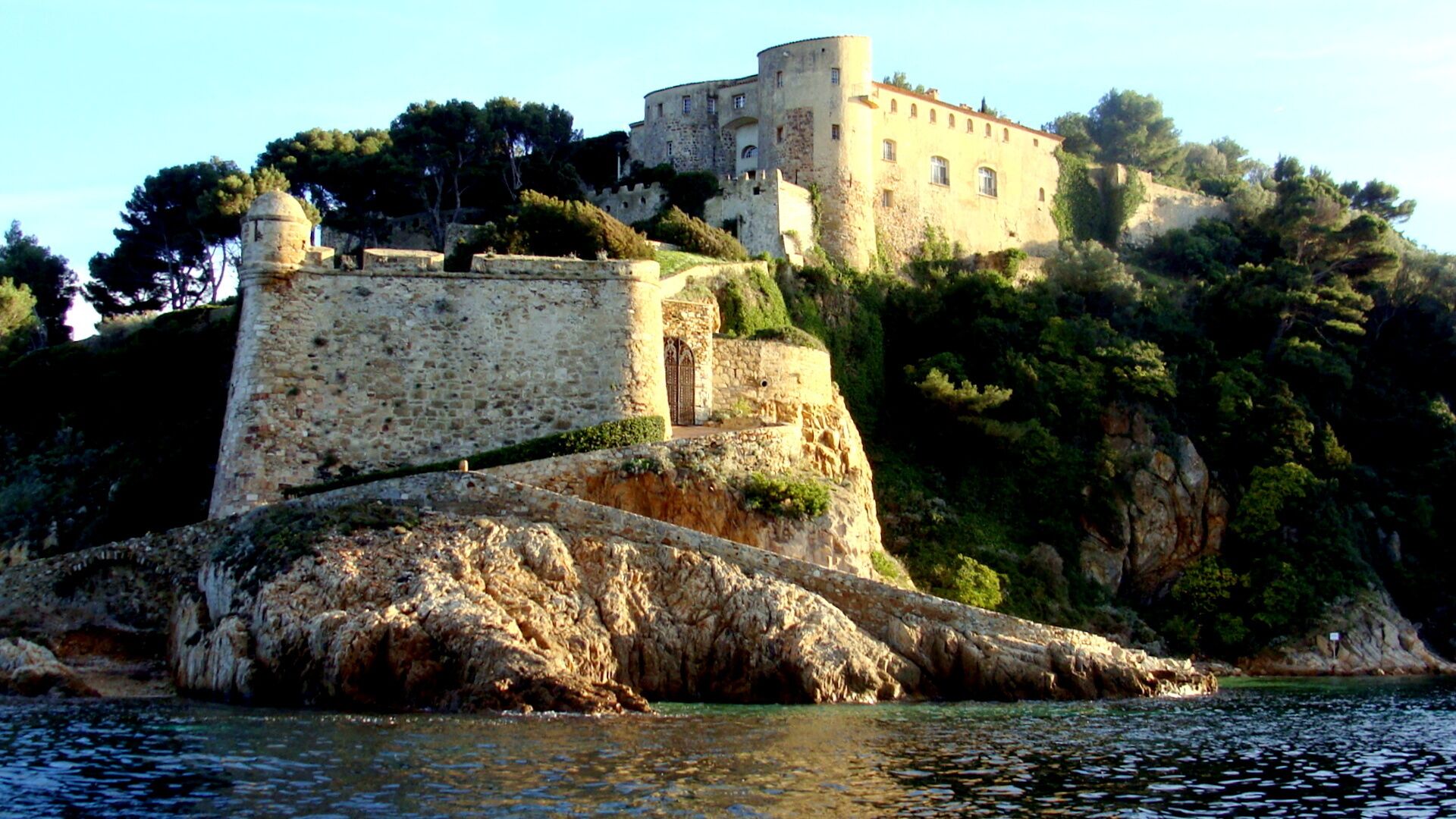 A historic stone castle on a rocky island with a clear view of the surrounding water.