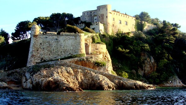 A historic stone castle on a rocky island with a clear view of the surrounding water.