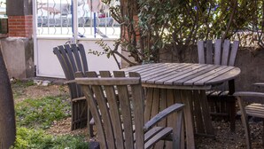 A wooden table and chairs set outdoors, surrounded by a brick wall and a metal gate. - 100m from the beach, apartment with river view, small garden for meals (Agde)