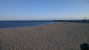 A wide sandy beach with a rocky breakwater and a lighthouse in the distance. - 100m from the beach, apartment with river view, small garden for meals (Agde)