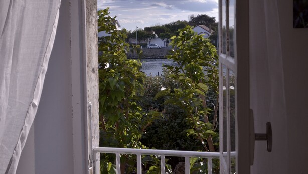 A view from a balcony with a railing, overlooking a body of water and buildings in the distance. - 100m from the beach, apartment with river view, small garden for meals (Agde)