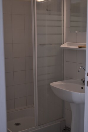 Un baño con cabina de ducha, lavabo y espejo.