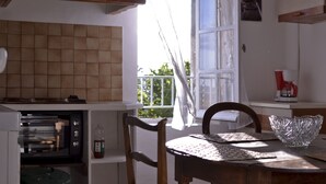 A kitchen with a built-in oven, a dining table with a glass bowl, and a view of greenery outside. - 100m from the beach, apartment with river view, small garden for meals (Agde)