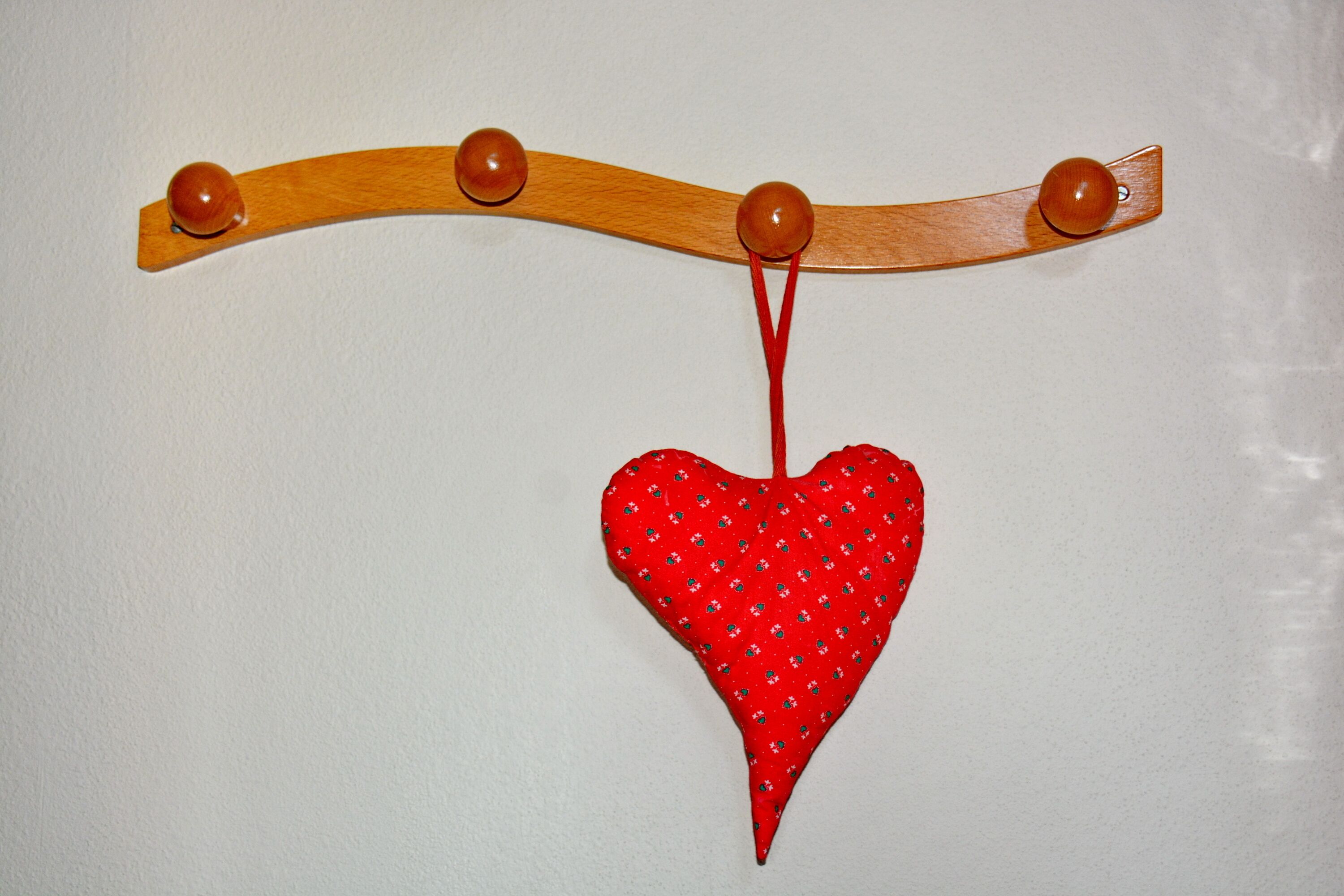 A wooden structure with four spherical knobs and a red heart-shaped object hanging from it.