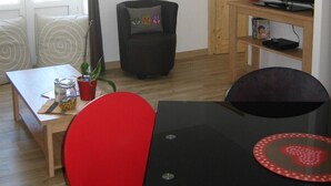 A living room with a TV, a red chair, a black table, and a wooden cabinet.